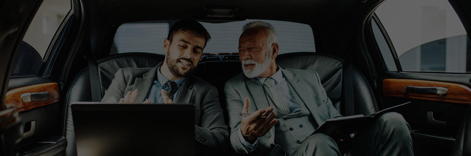 two businessman talking inside the car