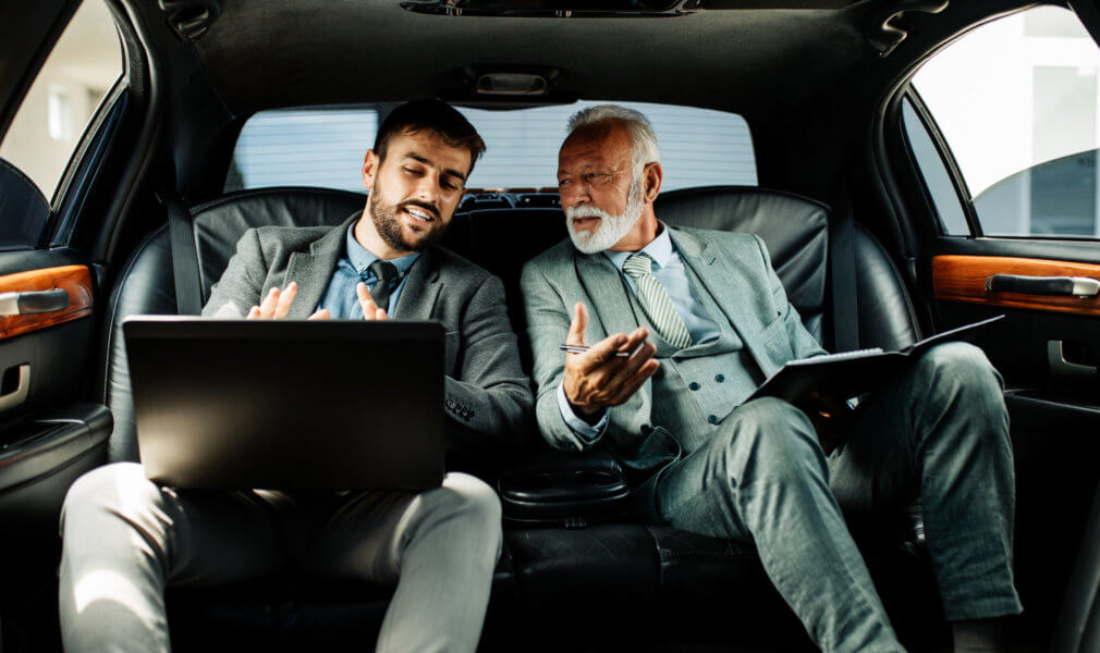 two businessman talking inside the car